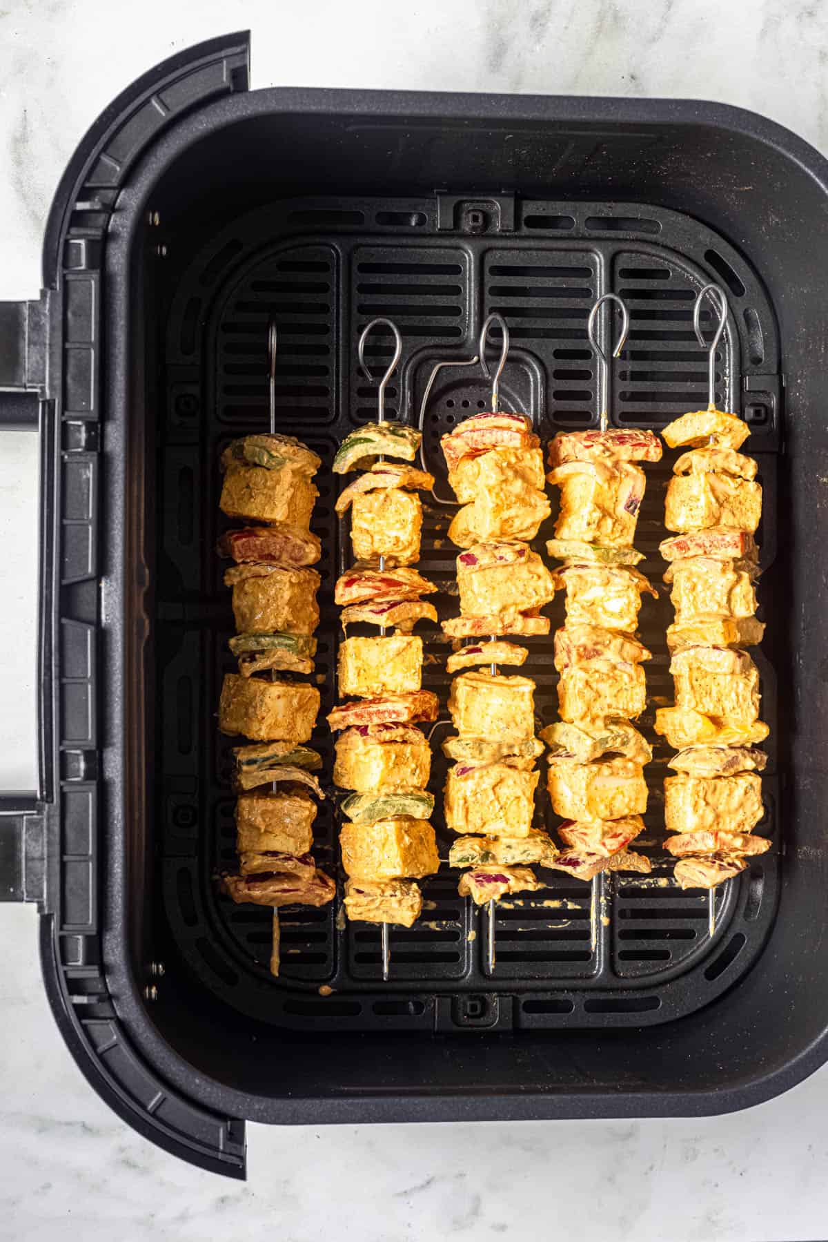 marinated paneer tikka skewers in air fryer basket