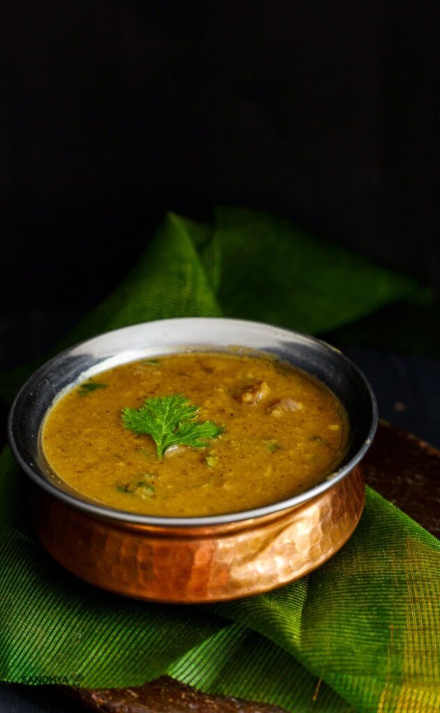 vengaya sambar served in a bowl in a green background
