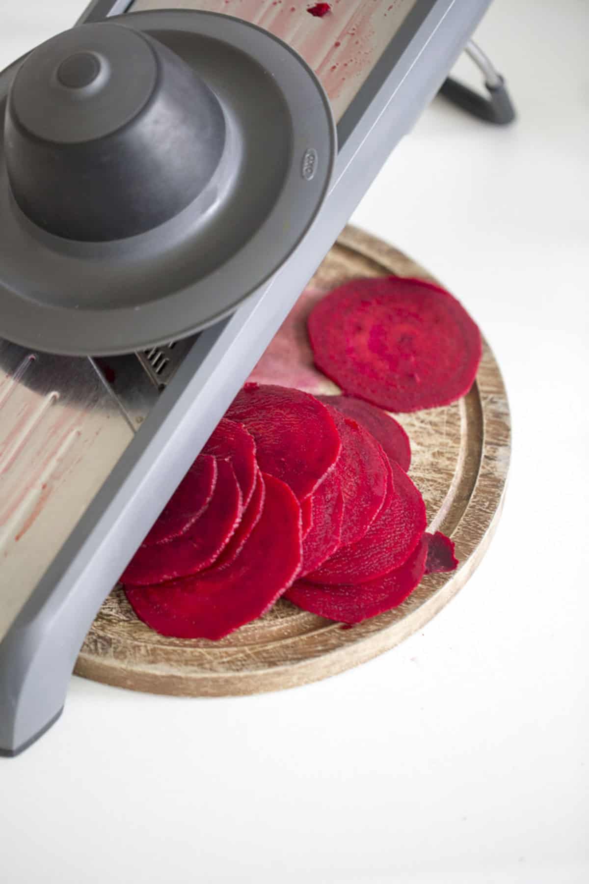 slicing red beets with a mandolin slicer for making beet chips.