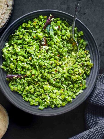 green beans poriyal served in a grey dish with chapatis.