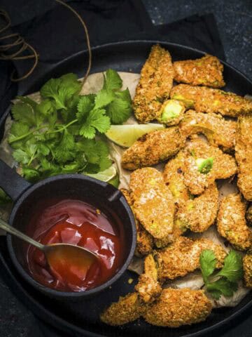 avocado fries in a serving dish with ketchup and coriander.