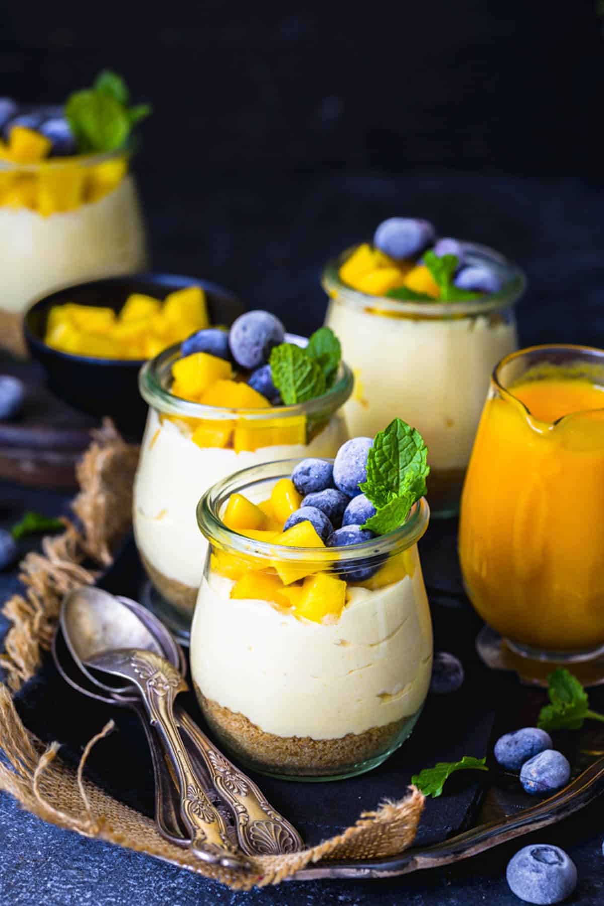 Creamy eggless no bake mango cheesecake in glass jars.