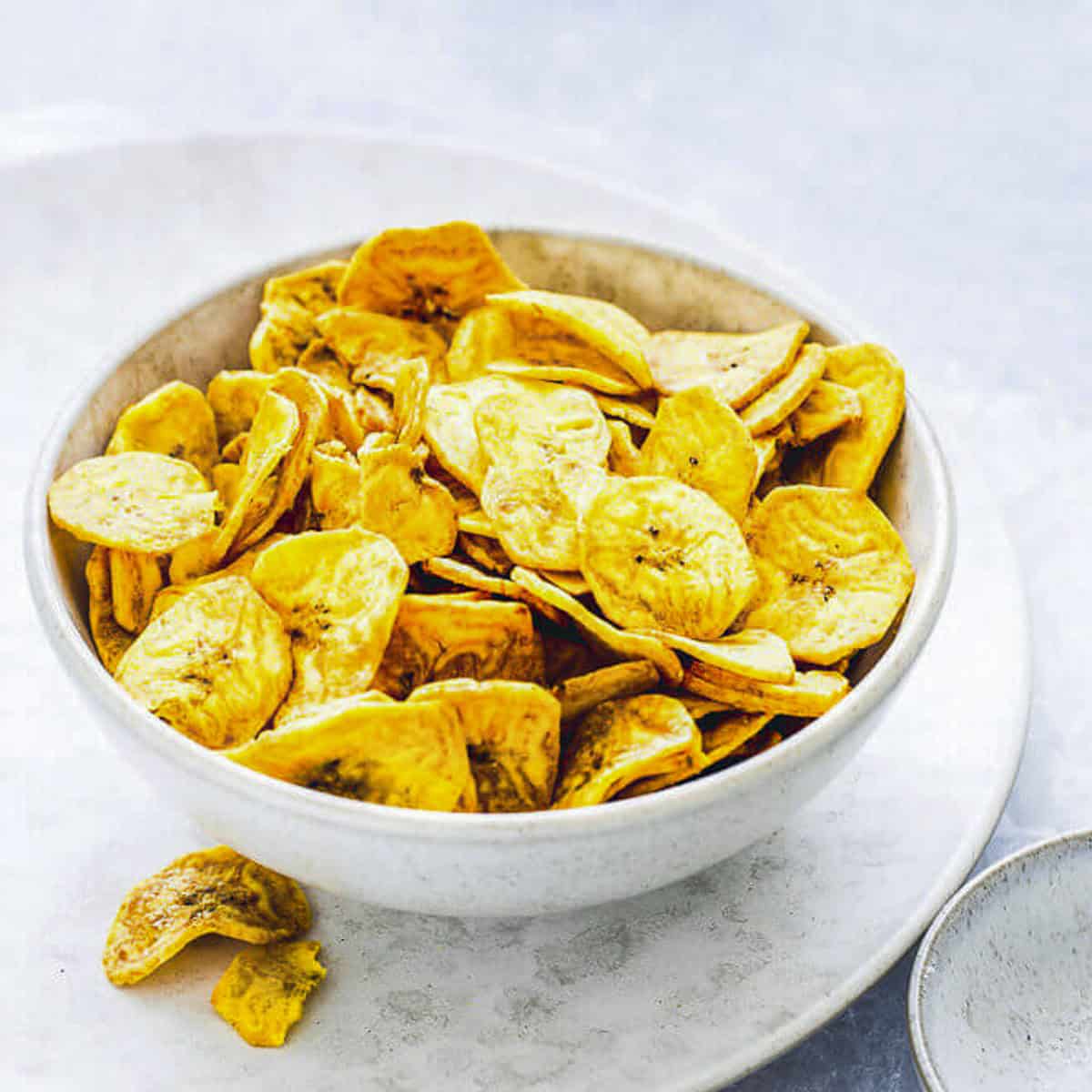 a white bowl of crispy air fryer Kerala plantain chips.