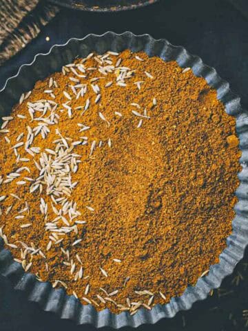 fresh homemade ground cumin powder in a black tray.