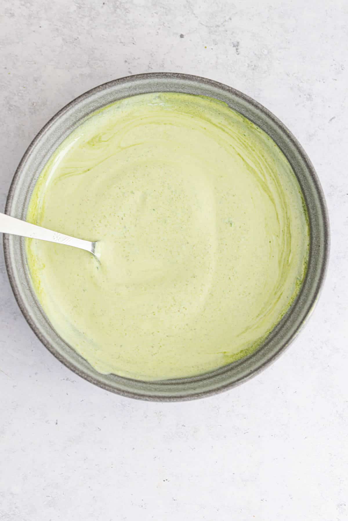 fresh yogurt mint sauce in a grey bowl with a spoon.