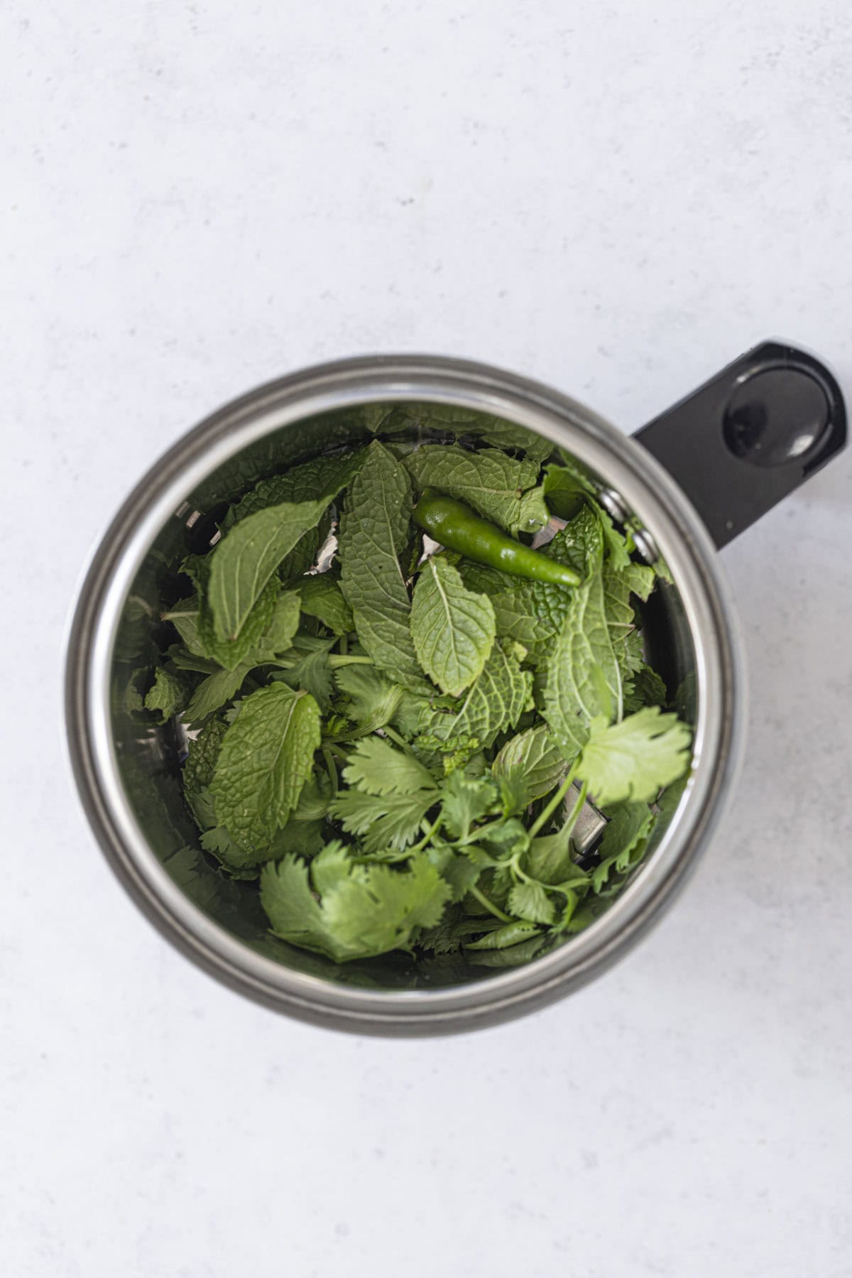 fresh herbs and green chilli in a blender jar to make mint coriander chutney.