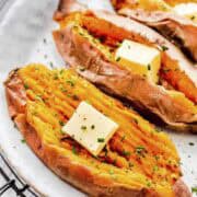 three perfectly cooked instant pot sweet potatoes topped with butter and chives.