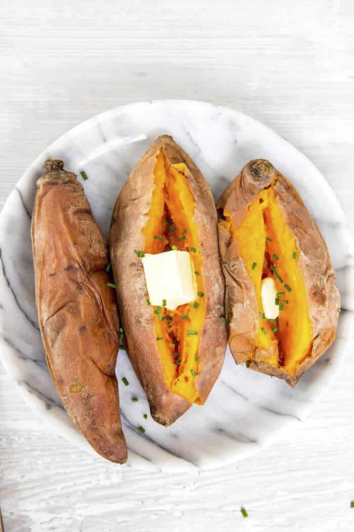 three perfectly cooked instant pot sweet potatoes on a white plate.