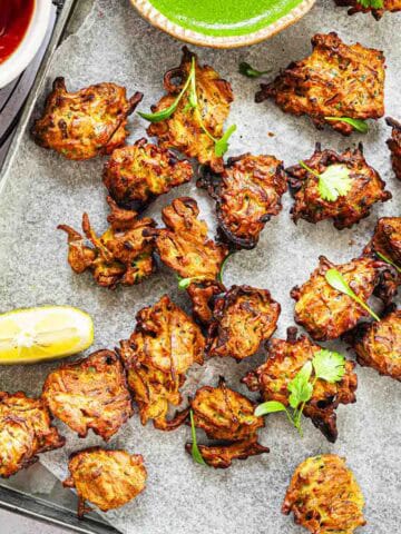 air fryer onion bhaji in a serving tray with green chutney and tomato ketchup.