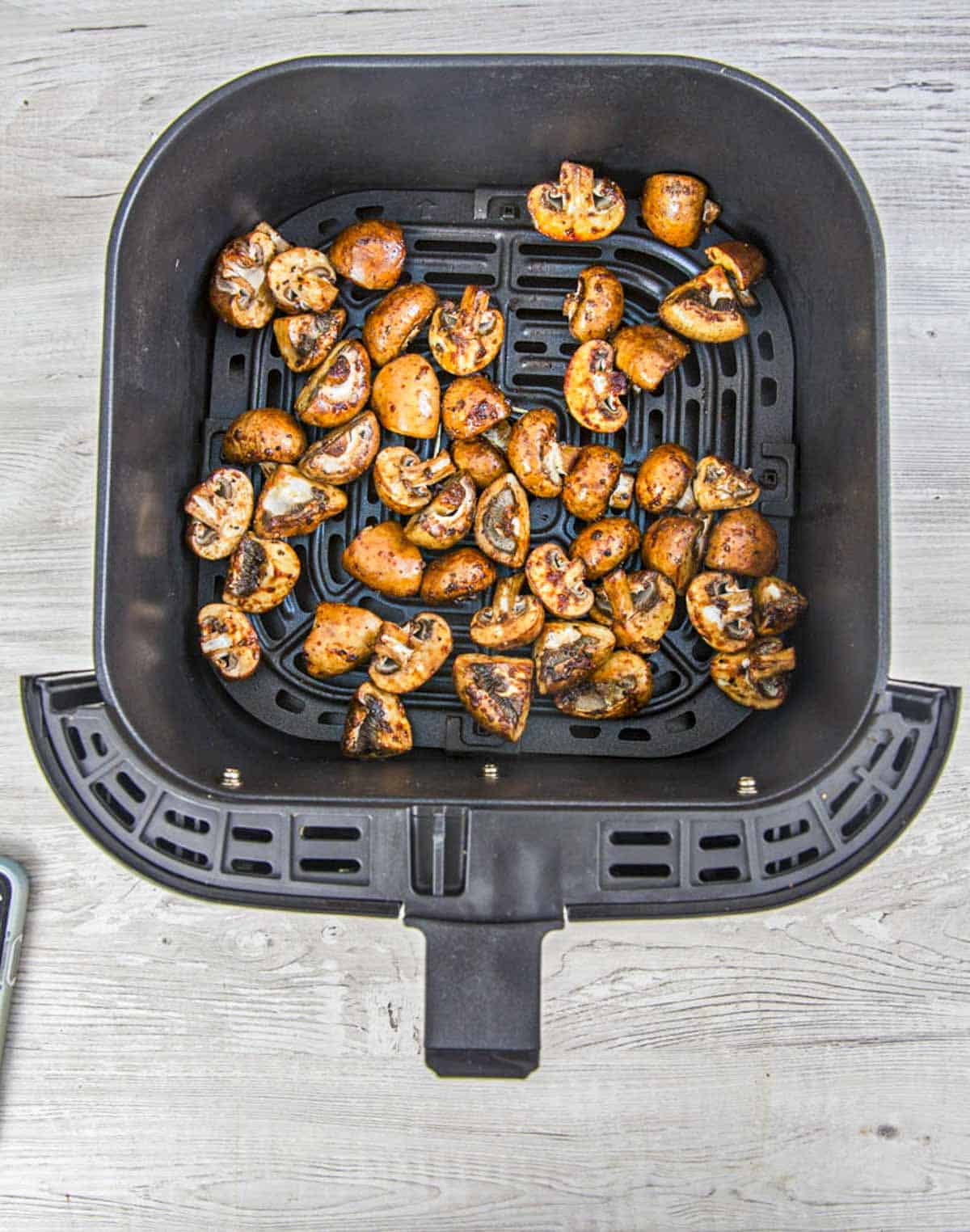 sliced mushrooms in air fryer basket.