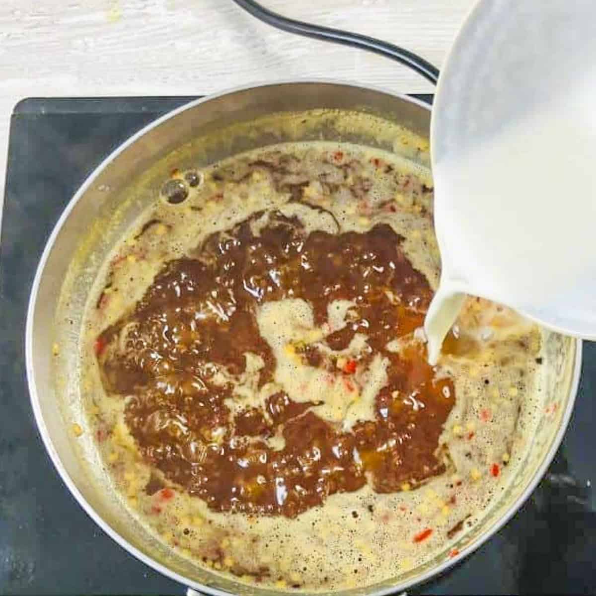 adding cornflour slurry to the sweet chilli sauce with pineapple.