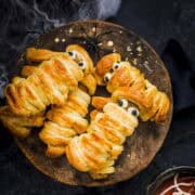 few sausage mummies made with puff pastry and served with spider web dip.