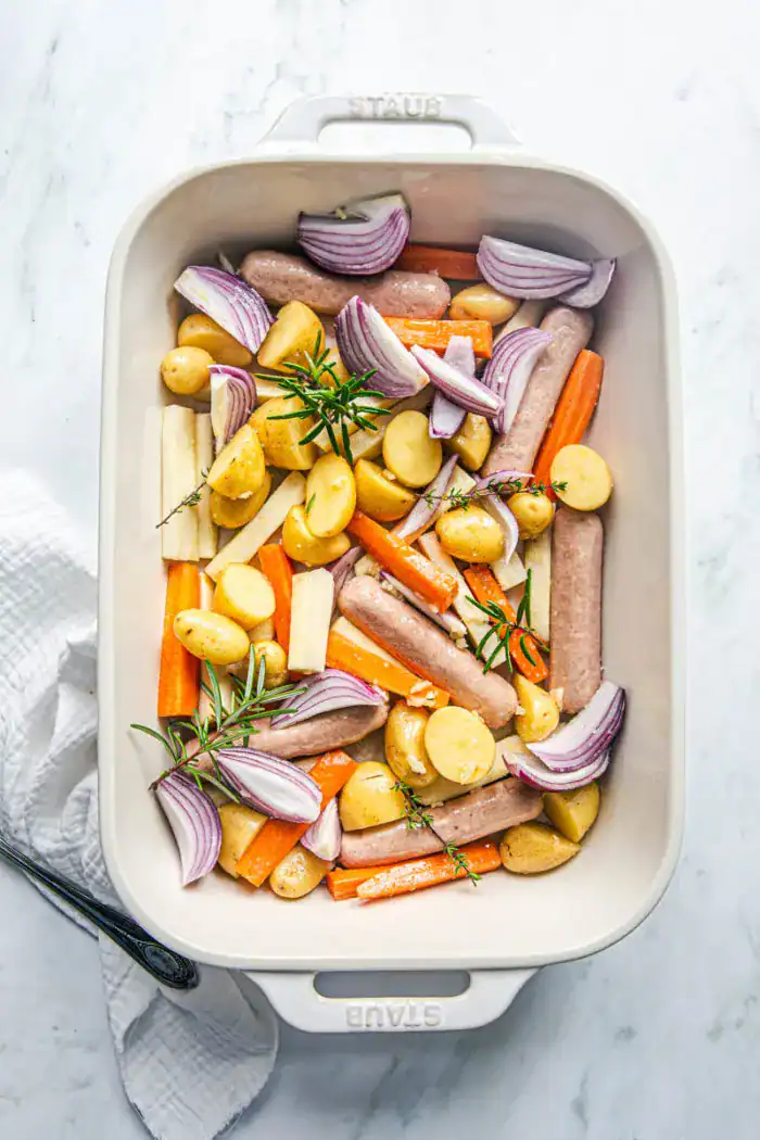 Root vegetables and veggie sausages in a tray bake for roasting.