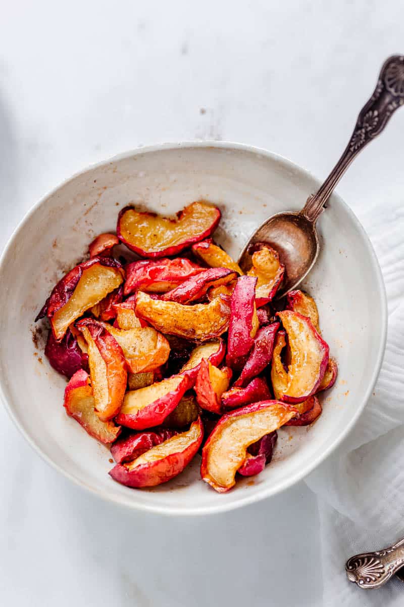 serve air fryer baked apples in a white bowl with a spoon.