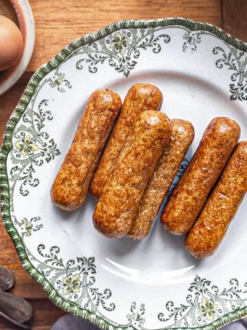 6 air fryer veggie sausages on a plate and served with air fryer eggs.