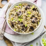 instant pot mushroom fried rice served in a white bowl with a pink napkin underneath.