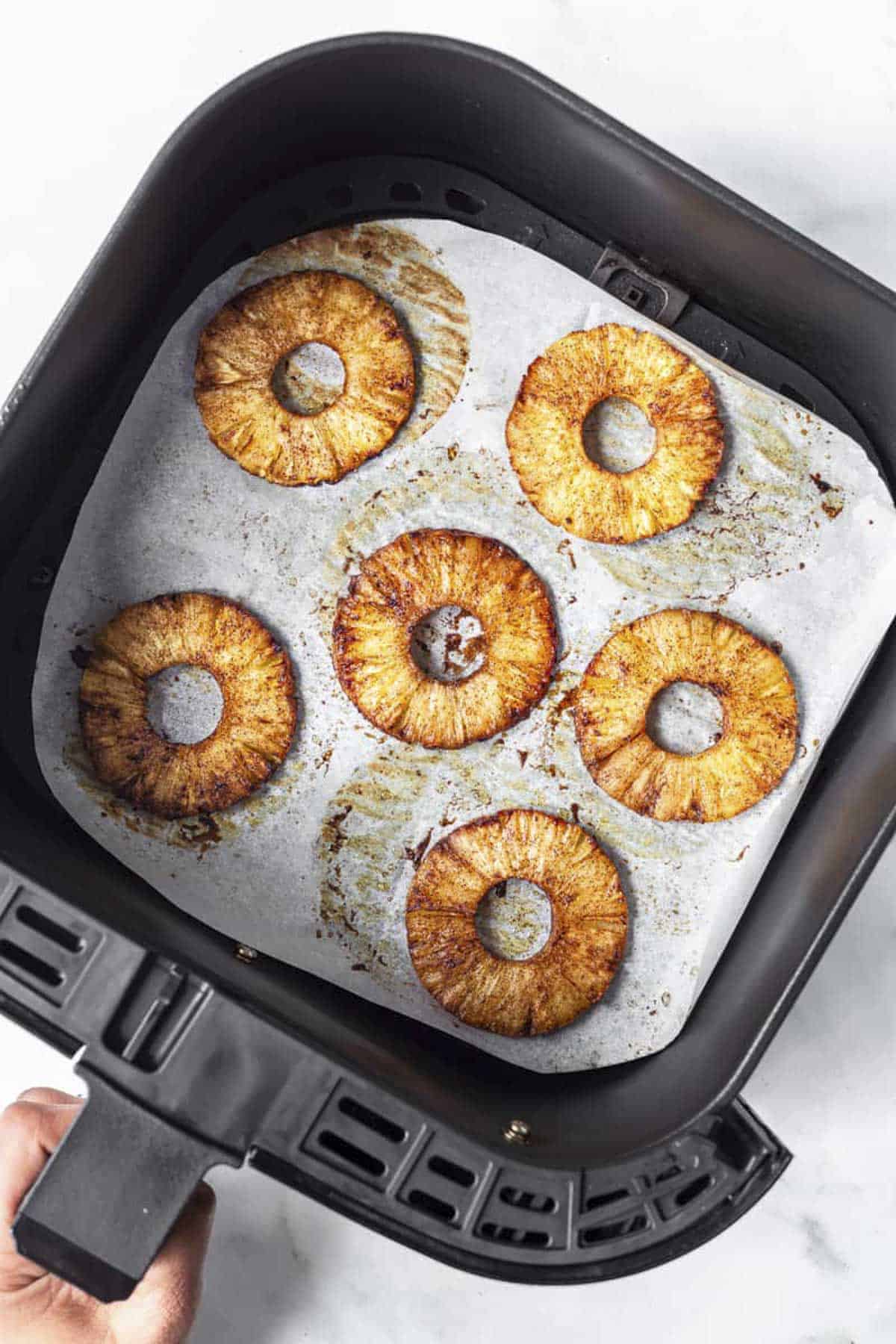 air fried pineapple slices in air fryer basket.