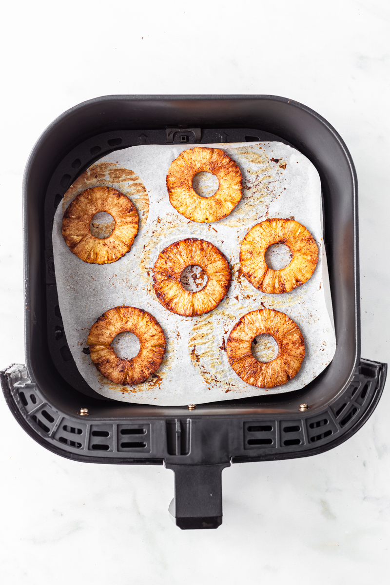 Airfryer pineapple slices in air fryer basket.