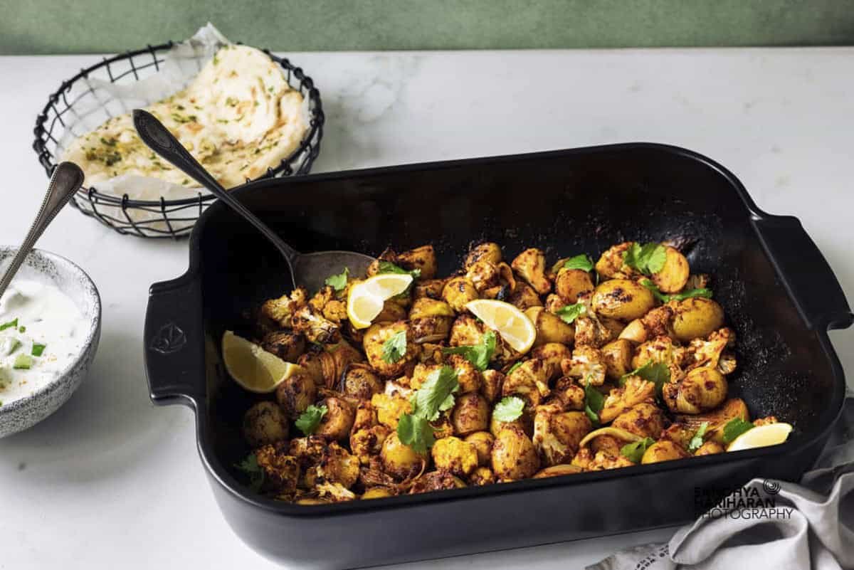 Indian potato cauliflower traybake served with naan and raita.