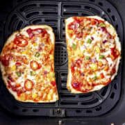 two air fryer bread pizza in the air fryer basket.