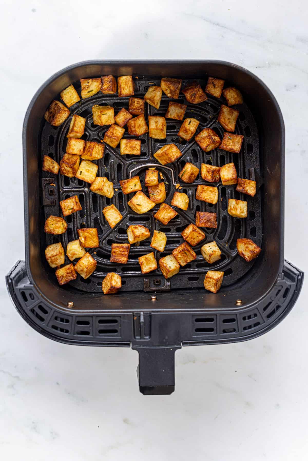 crispy cubes of potatoes in air fryer basket