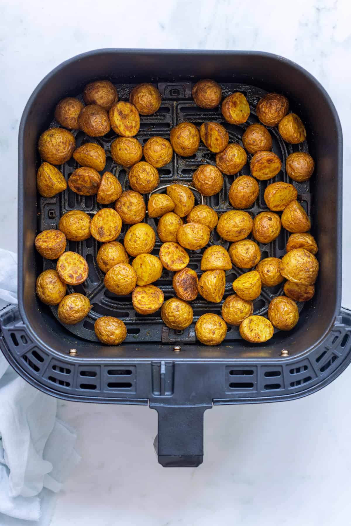 crispy air fried indian potatoes in air fryer basket.