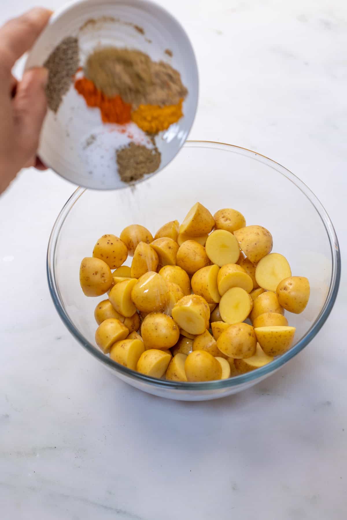 add spices to the halved baby potatoes for roasting in the air fryer.
