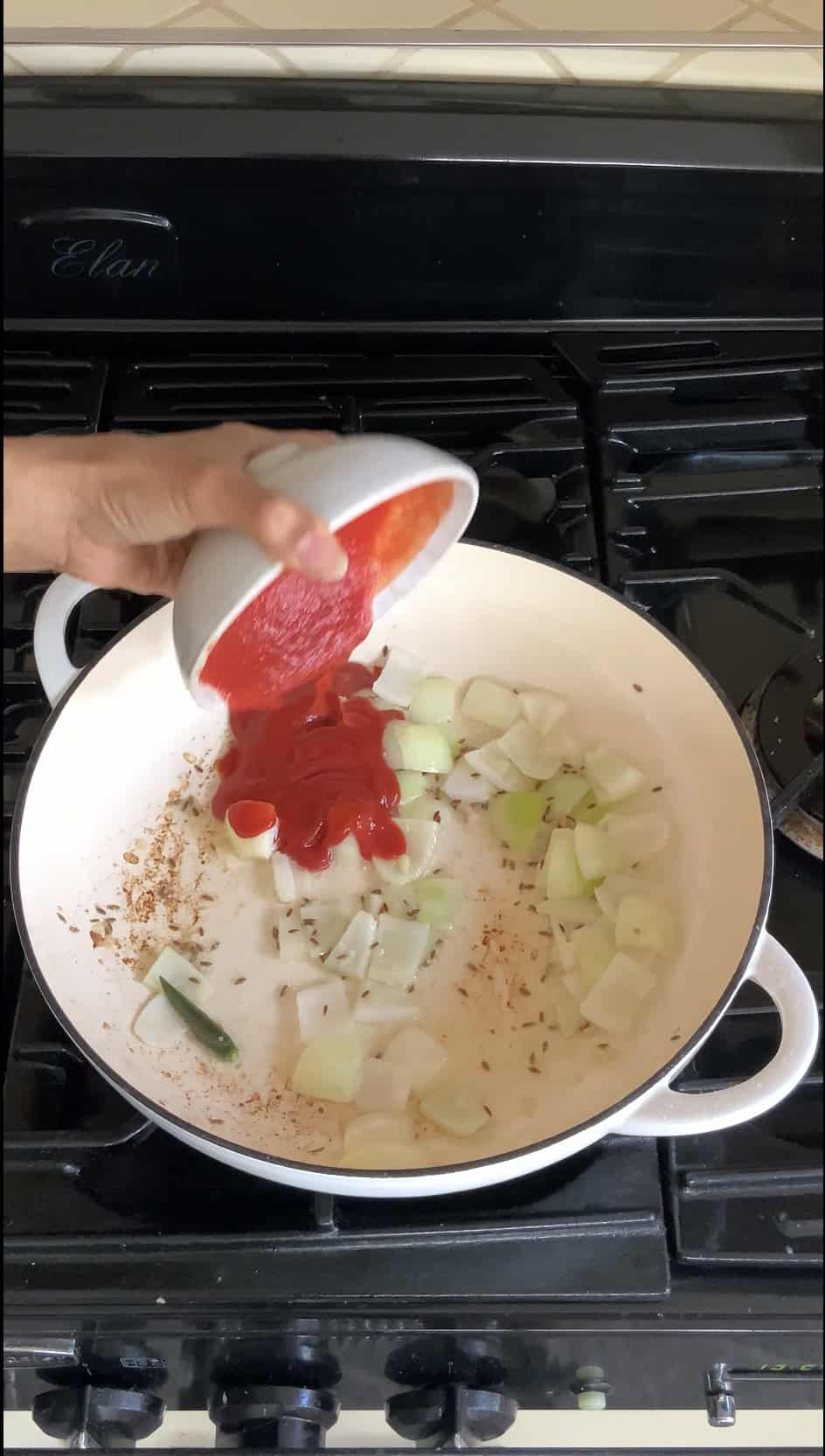 adding passata sauce and ketchup to the pan.
