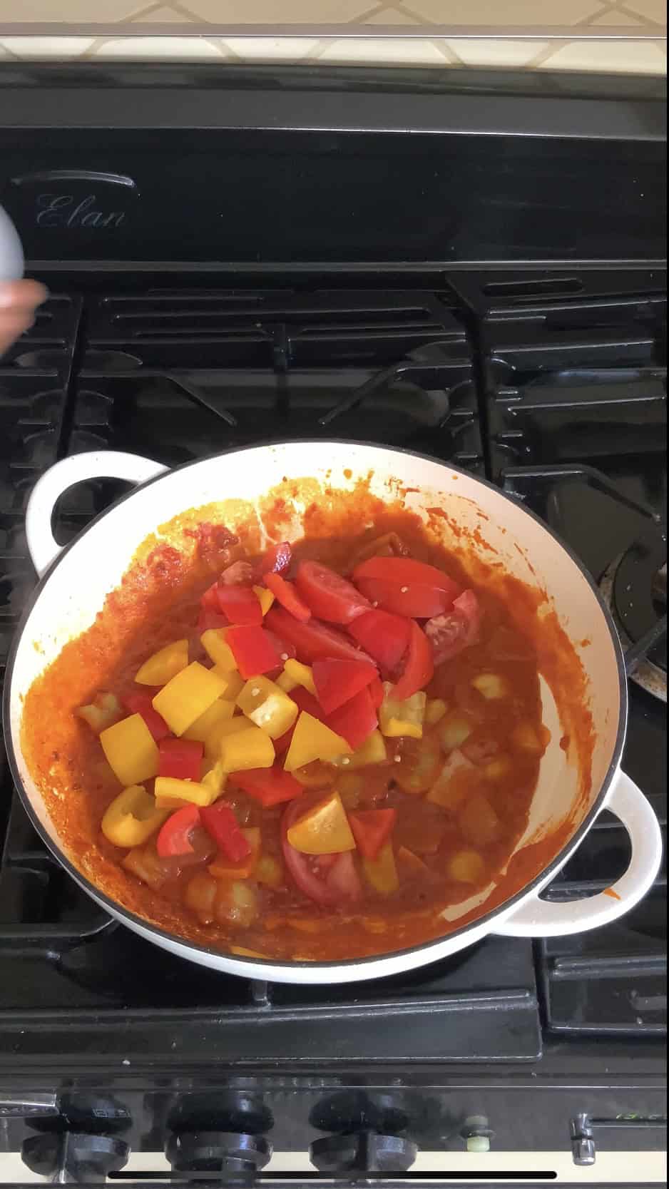 Adding peppers and tomatoes to the pan for jalfrezi.