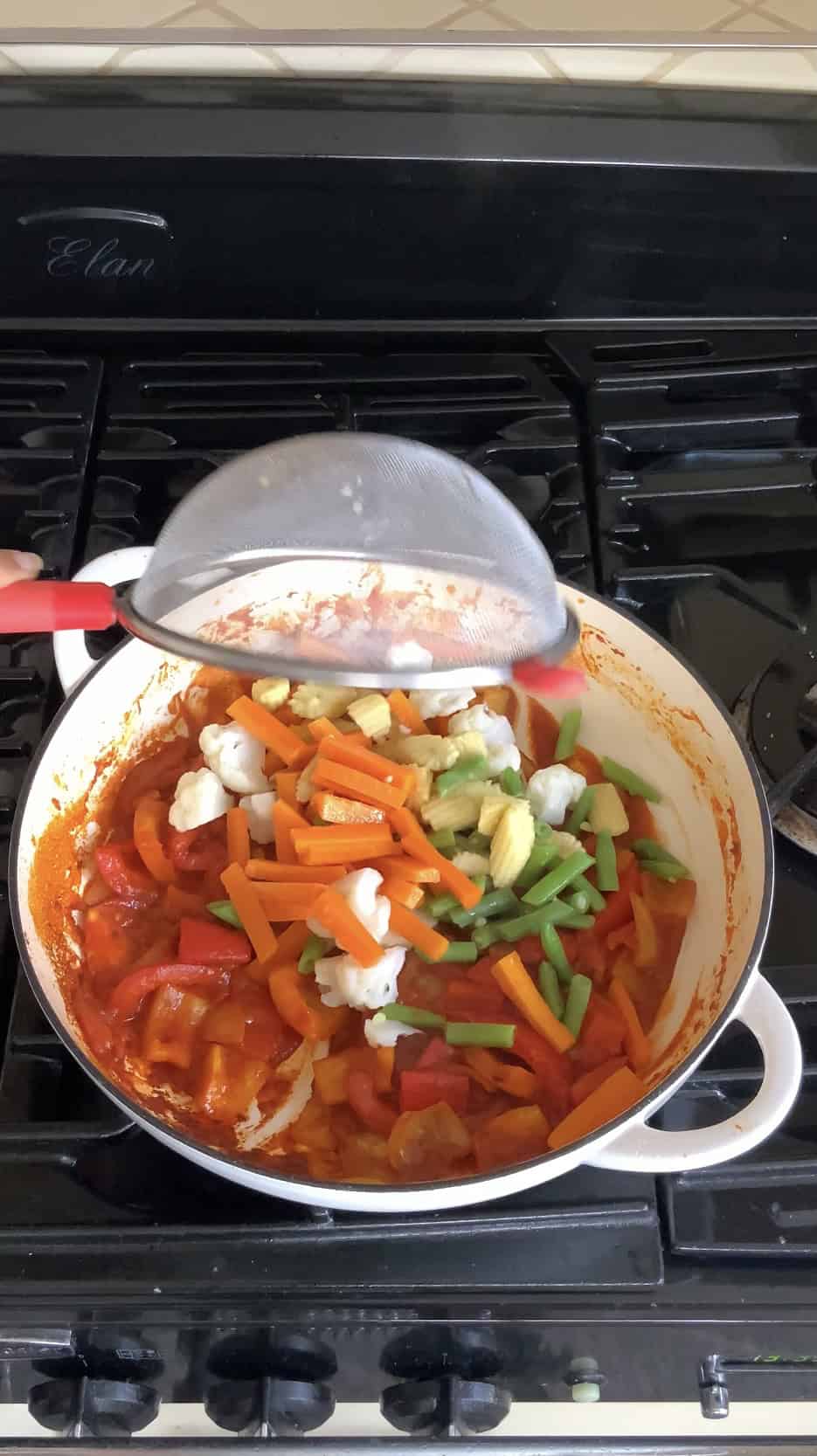 Adding blanched vegetables to the pan for jalfrezi.