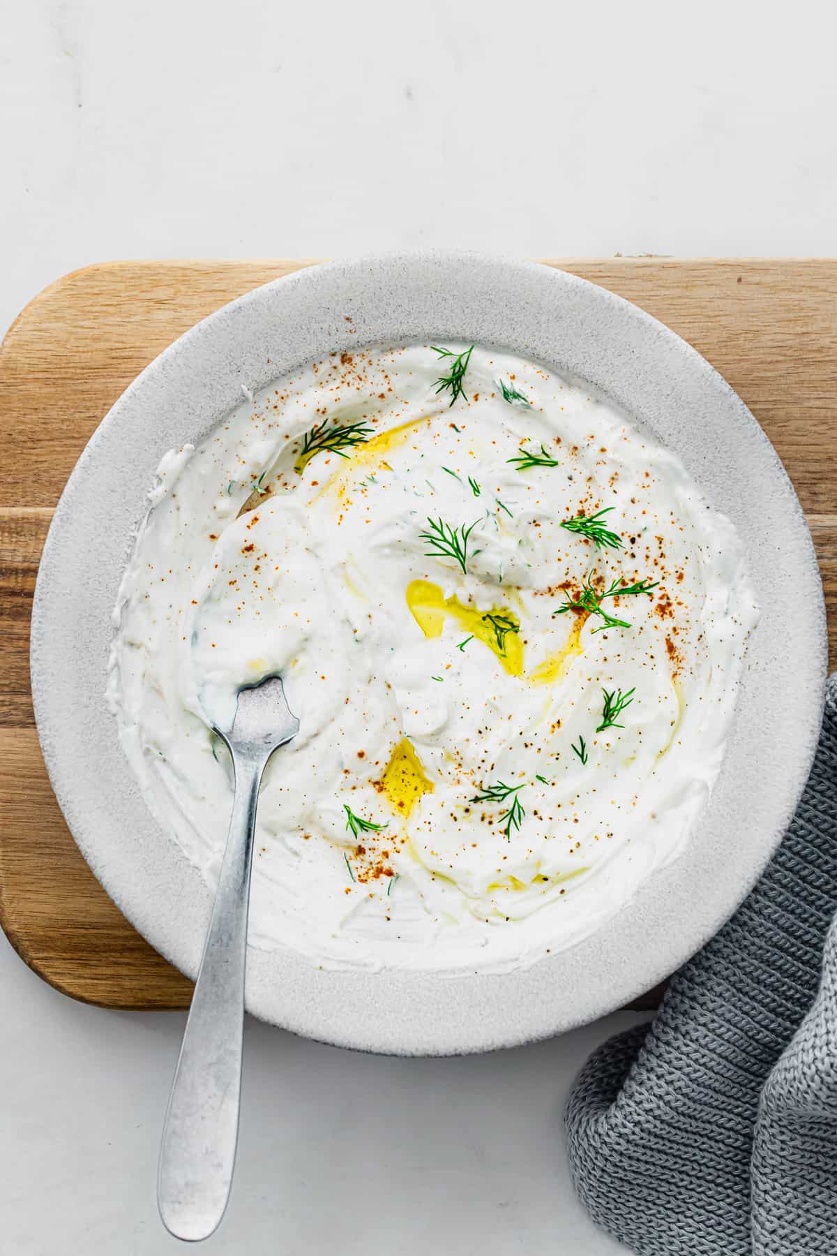yoghurt dill sauce in a white bowl with a spoon.