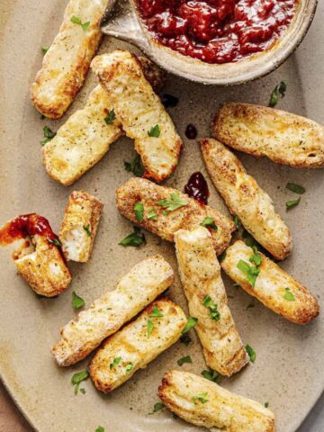halloumi fries served with bright red dipping sauce.