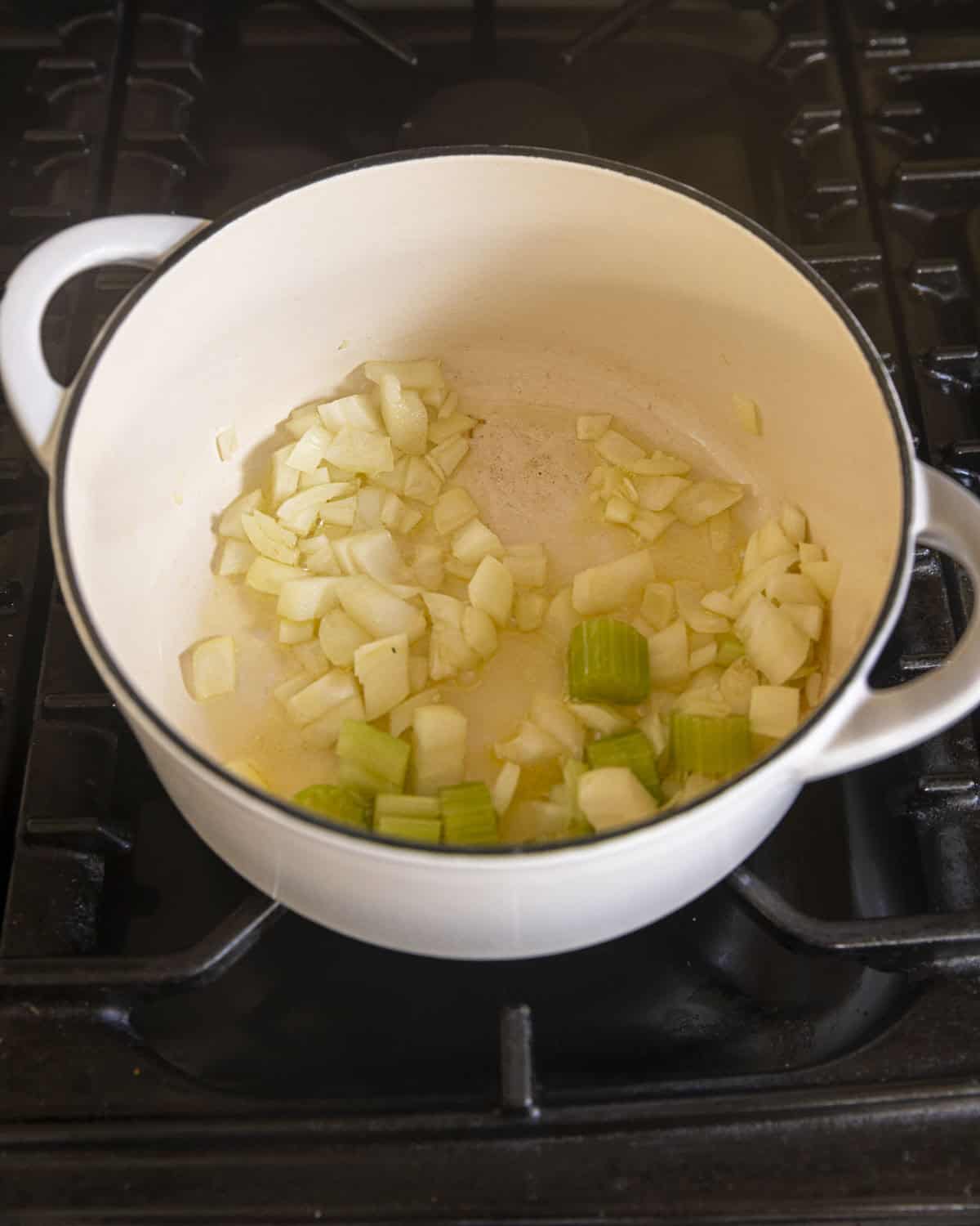 onion, garlic and celery in a white pot.