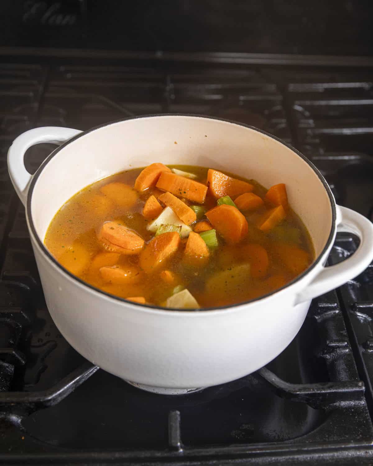 carrots, potato, stock and spices simmering in the pot to make carrot coriander soup.