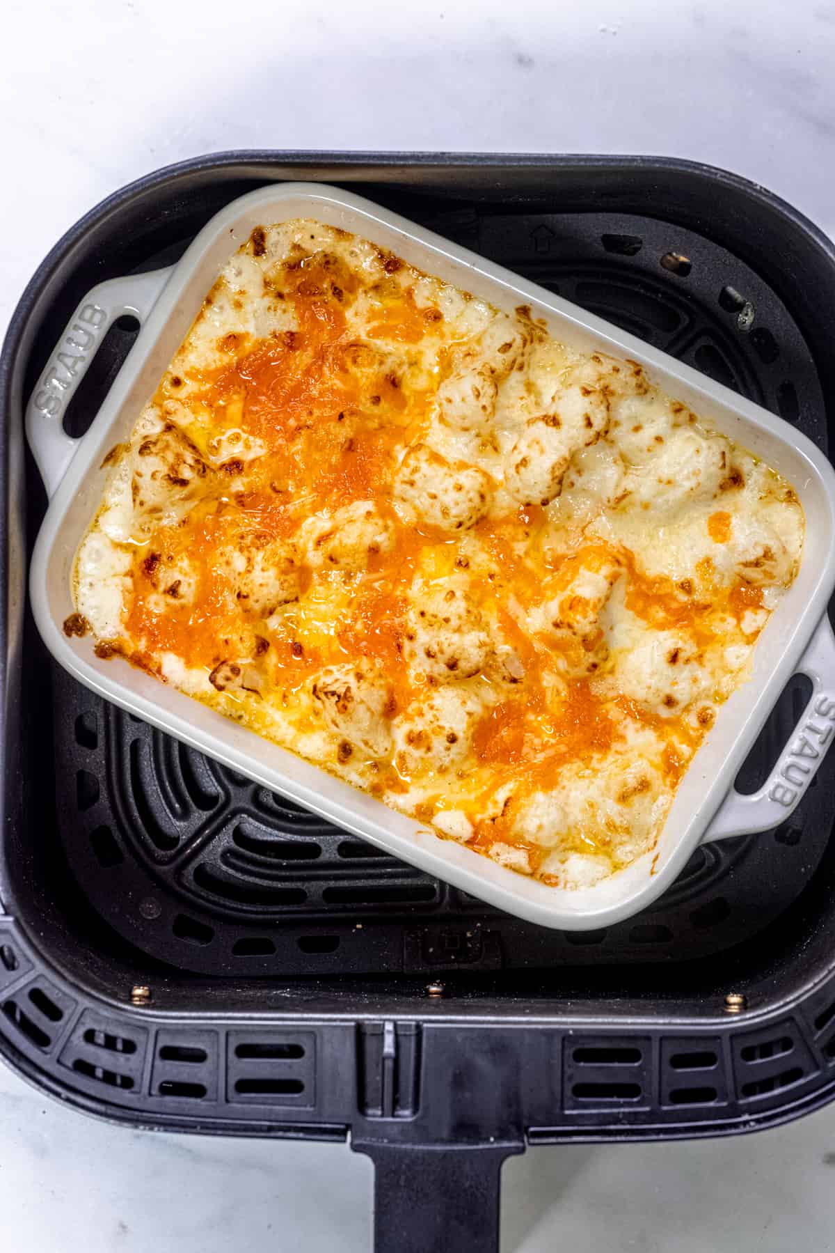 Cauliflower Cheese in air fryer basket.