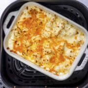 cauliflower cheese in air fryer basket.