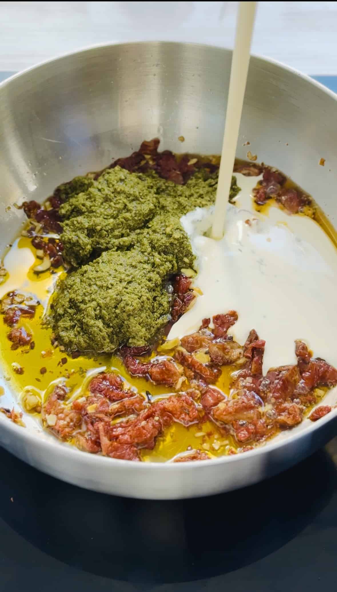 add pesto and cream to make creamy pesto gnocchi.