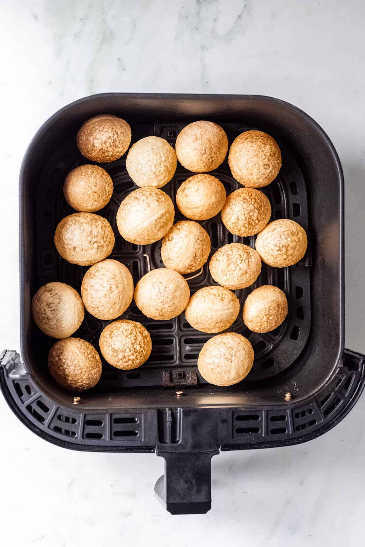 22 air fried pani puris in air fryer basket.