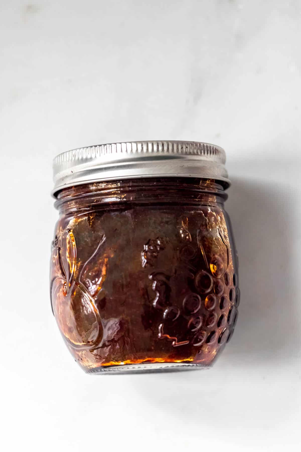 homemade vegan stir fry sauce in a small mason jar on white background.