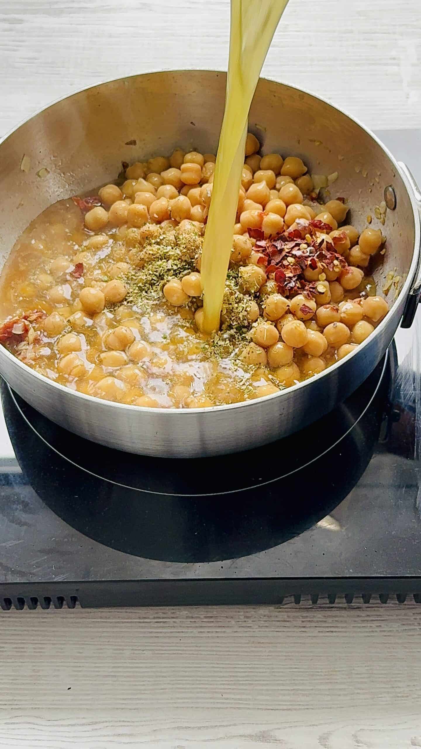 chickpeas, sundried tomatoes, vegetable stock in a steel pan.