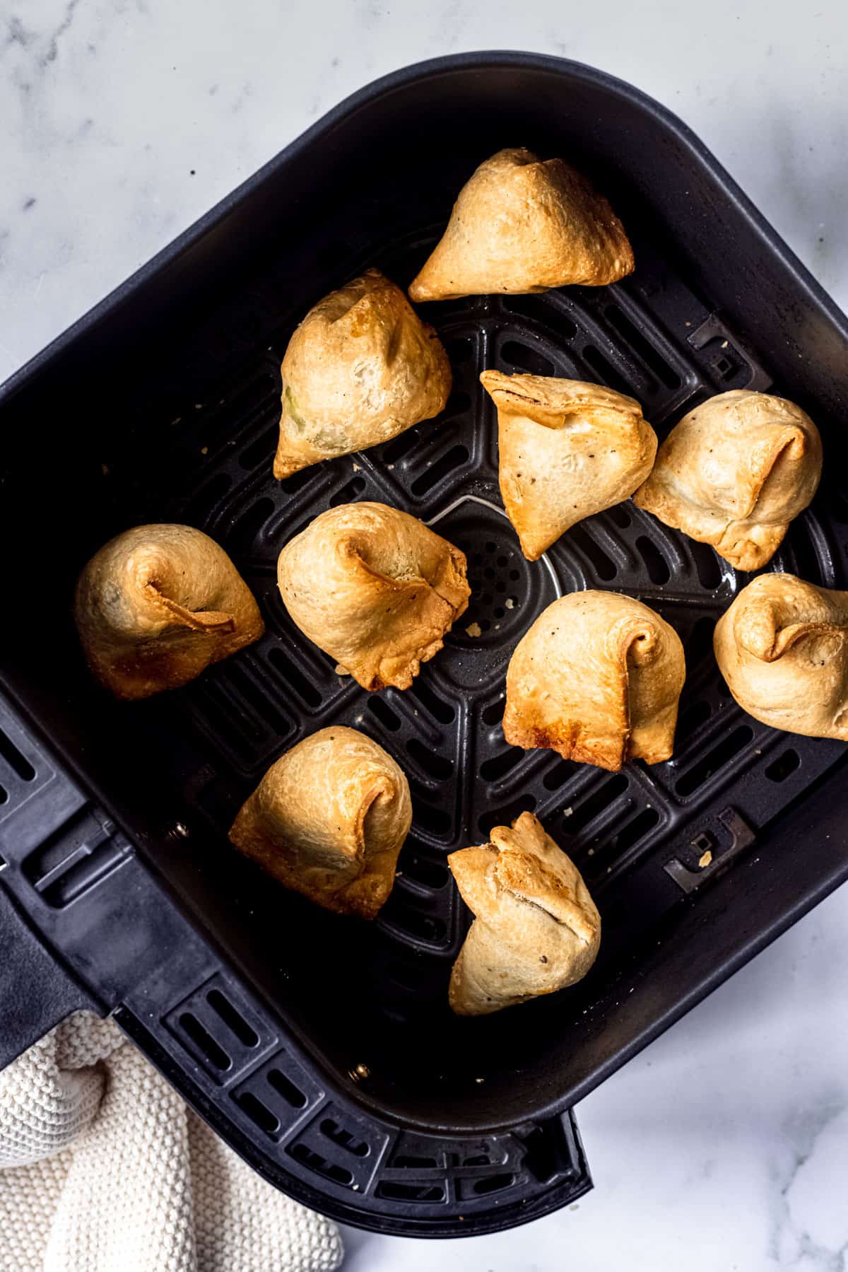 frozen samosas cooked in air fryer in the basket.