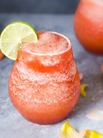 watermelon frozen rose in two glasses served with lime wedges.