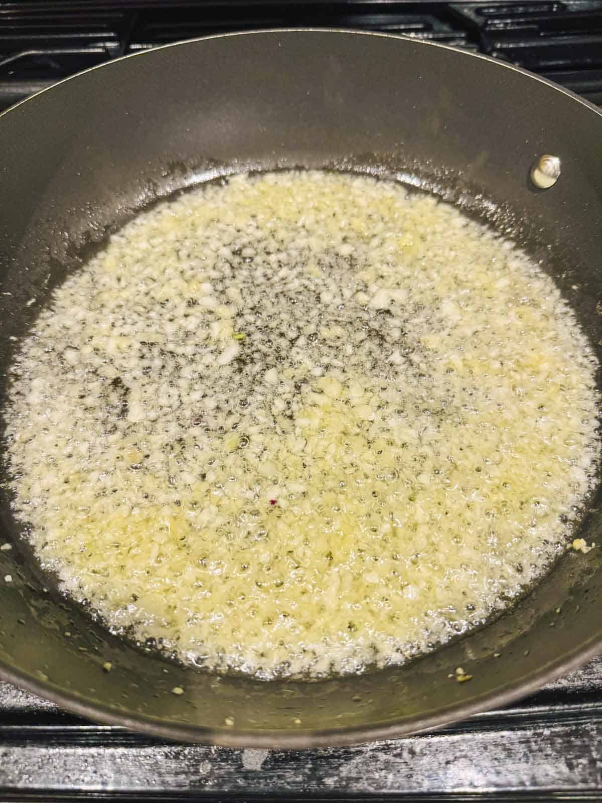 garlic, ginger are frying in oil in a pan.