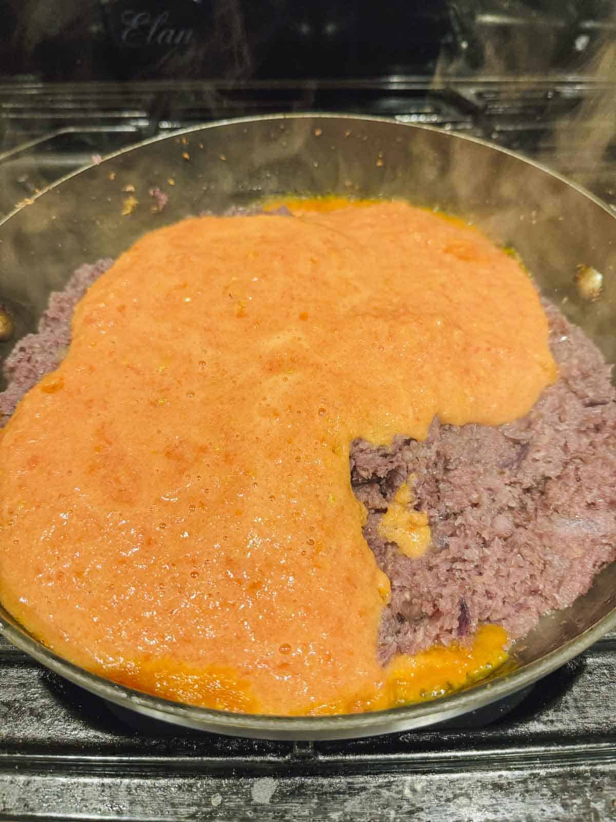 pureed tomatoes on top of fried onion in the pan.