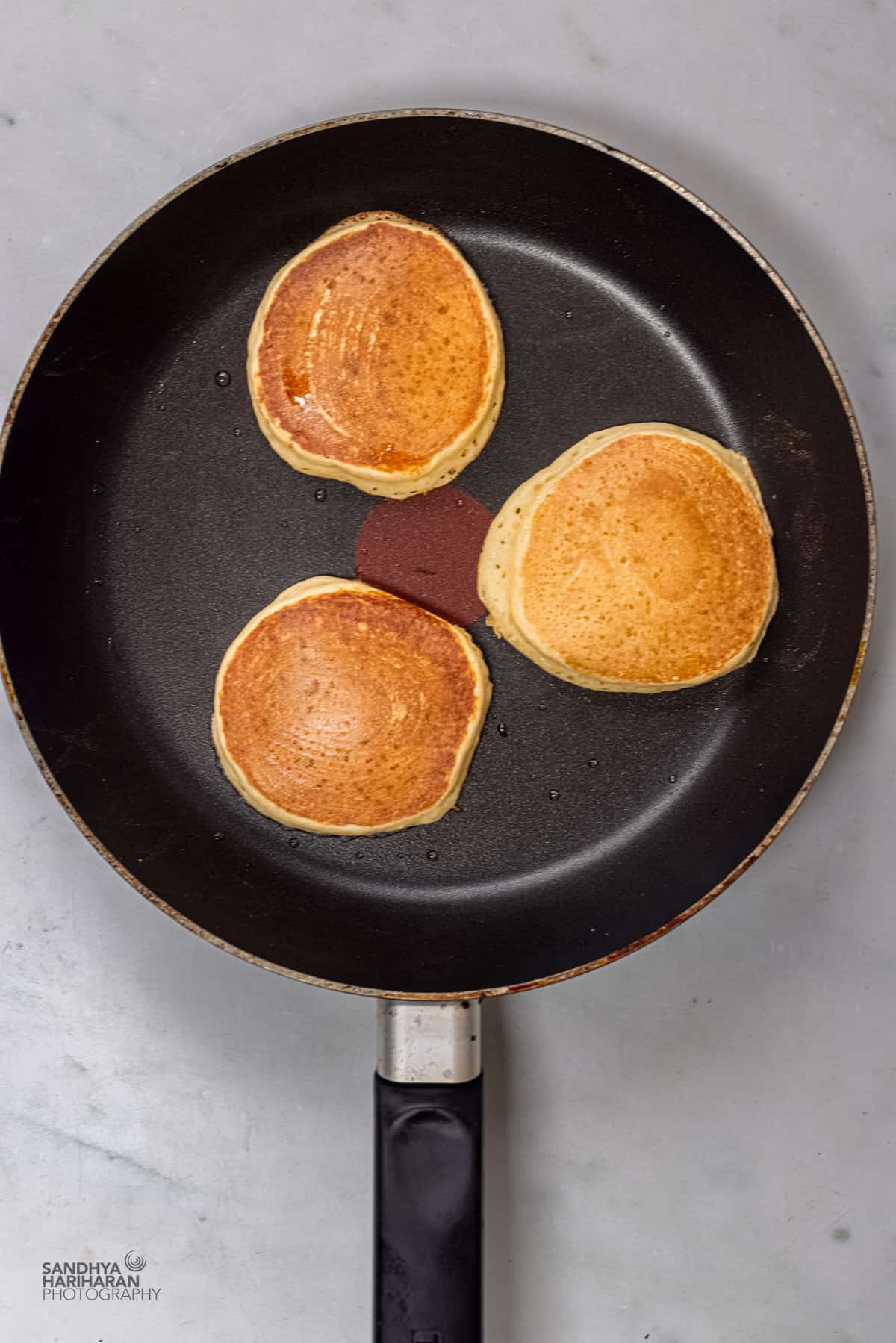 3 cooked mango pancake in a skillet.