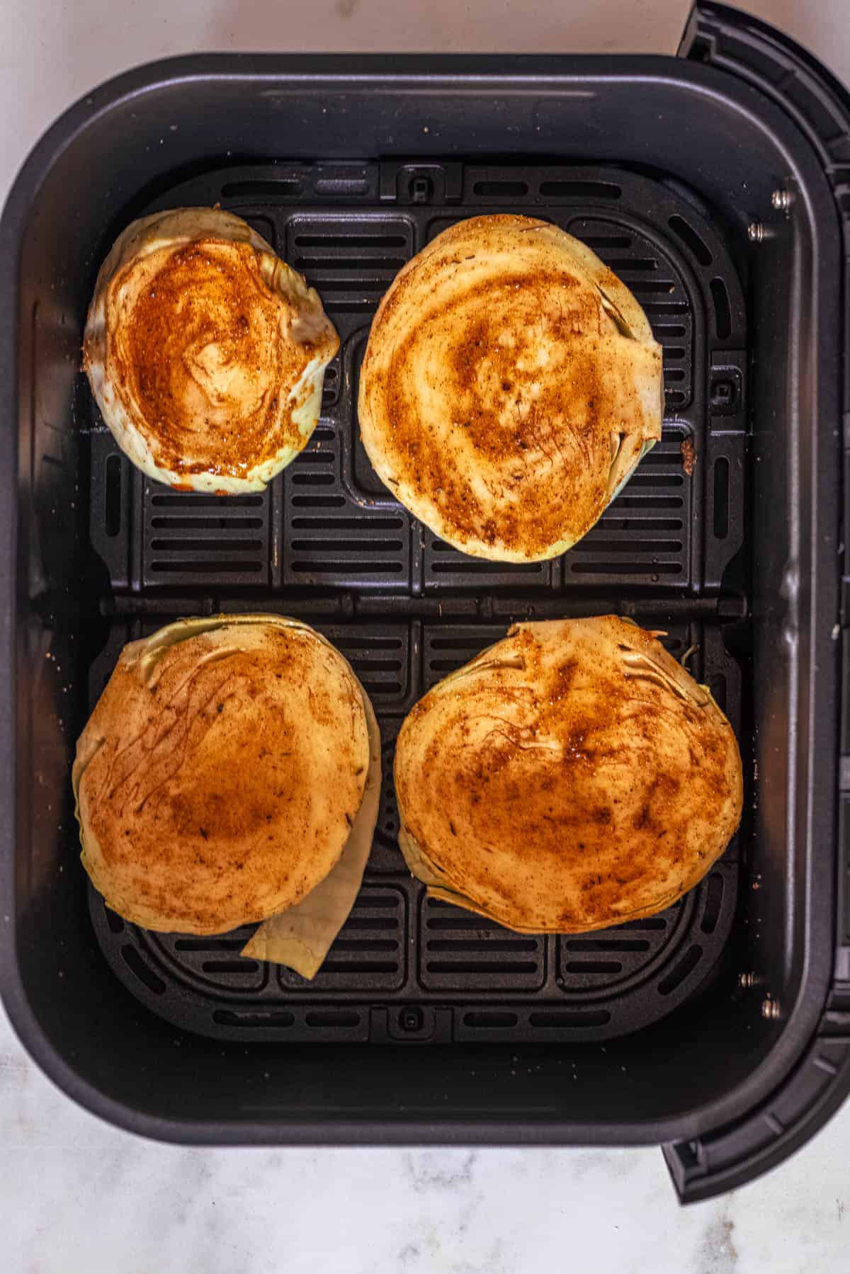 marinated cabbage steaks in air fryer basket.