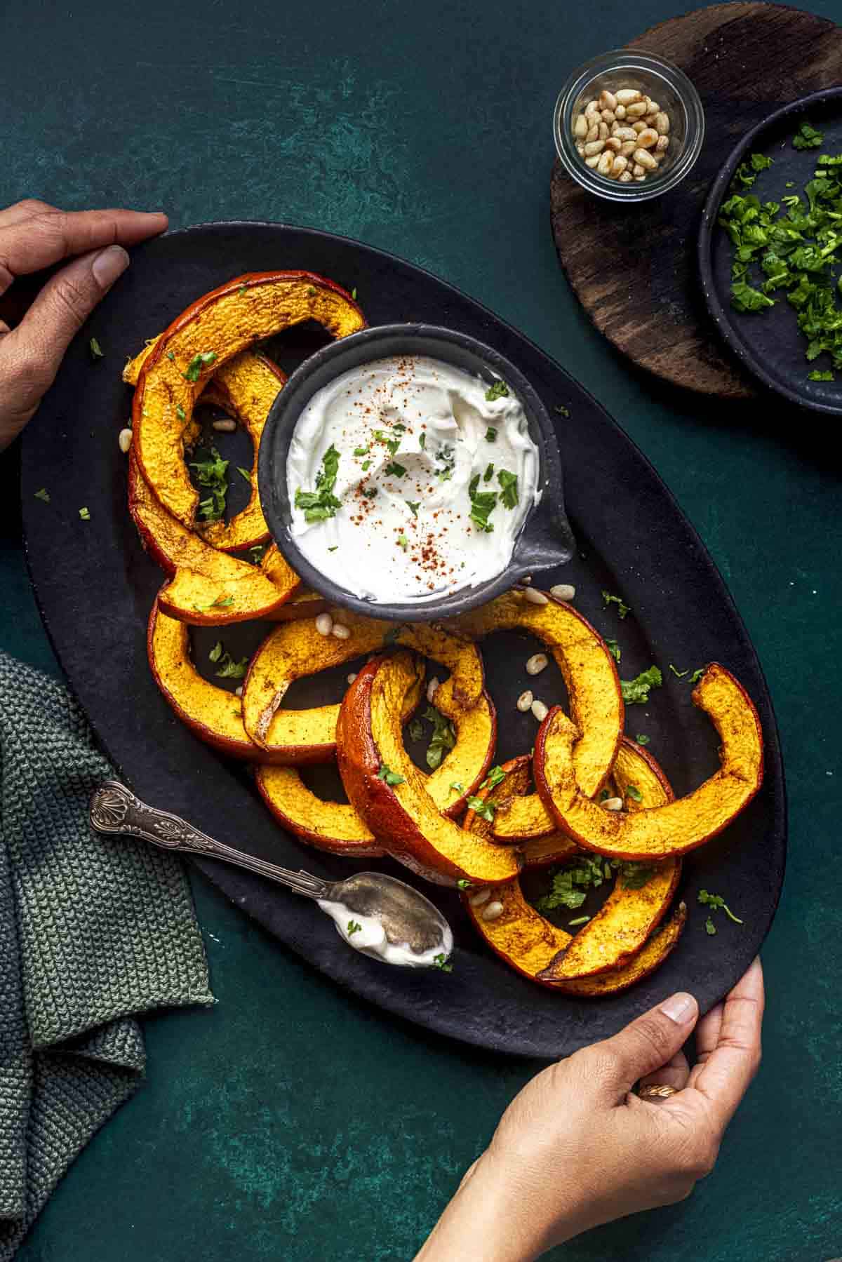 roasted air fryer pumpkin slices on a black oval serving tray with a sour cream dip.