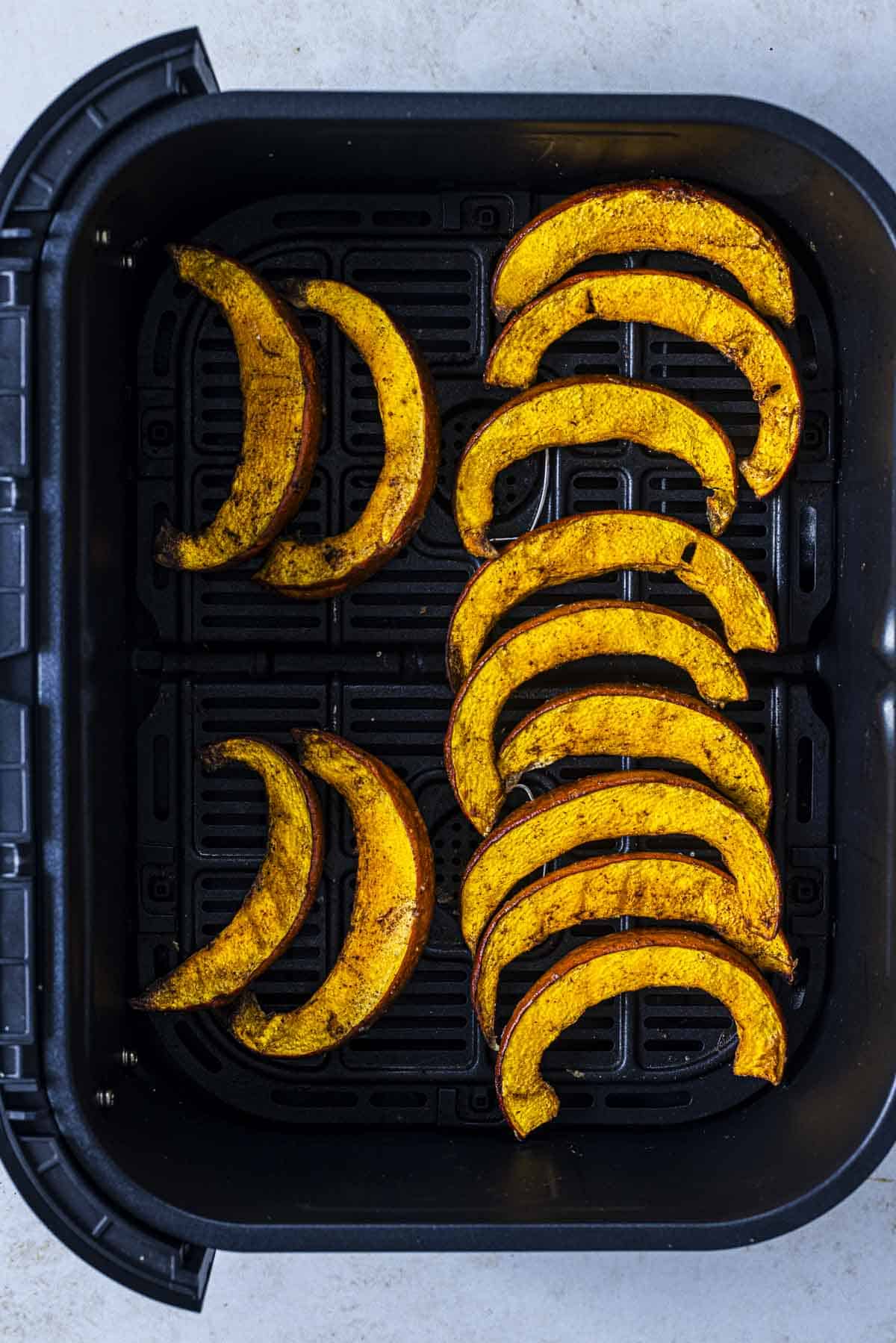 roasted pumpkin slices in air fryer basket.