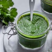 cilantro chutney in a jar with a spoon.