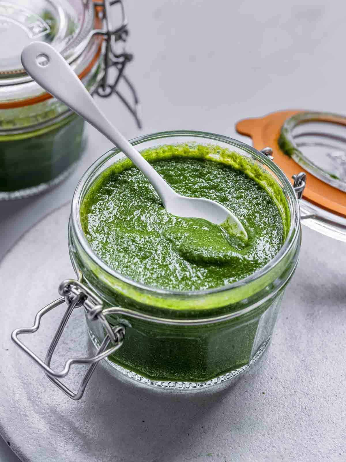 cilantro chutney in a jar with a spoon.